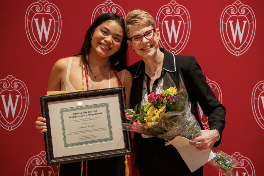 Two women smiling with a plaque and flowers
